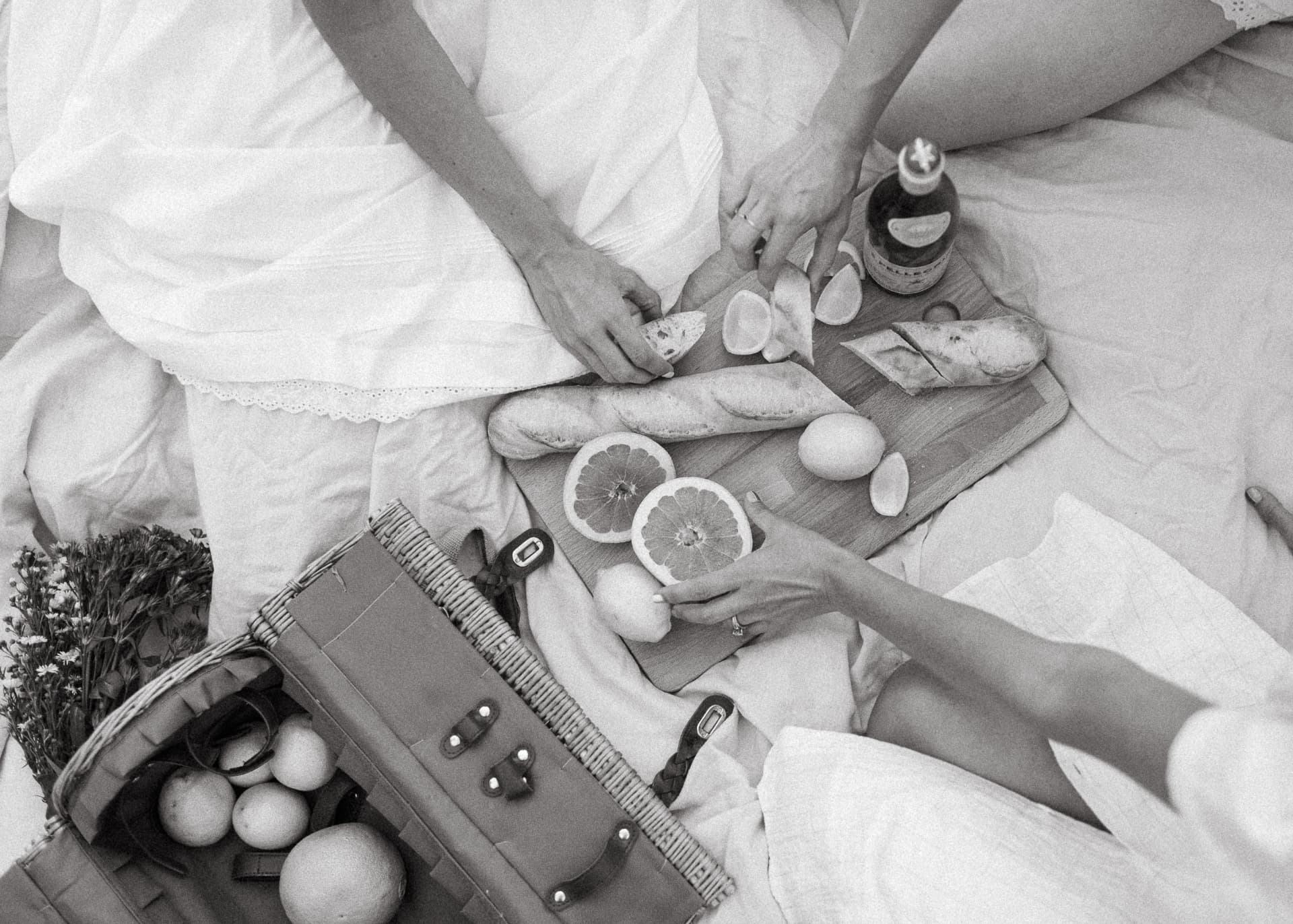 Overhead picnic spread on white linen, black and white
